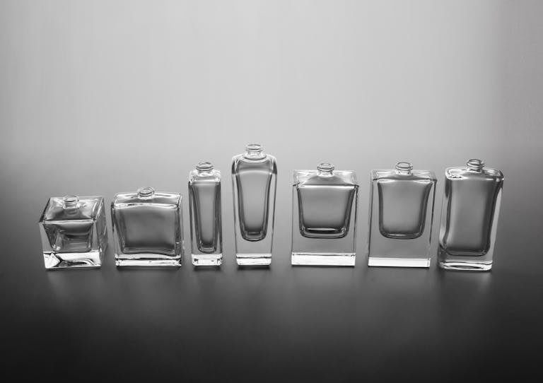 A sophisticated display of empty glass perfume bottles arranged against a neutral background, epitomizing minimalist elegance.
