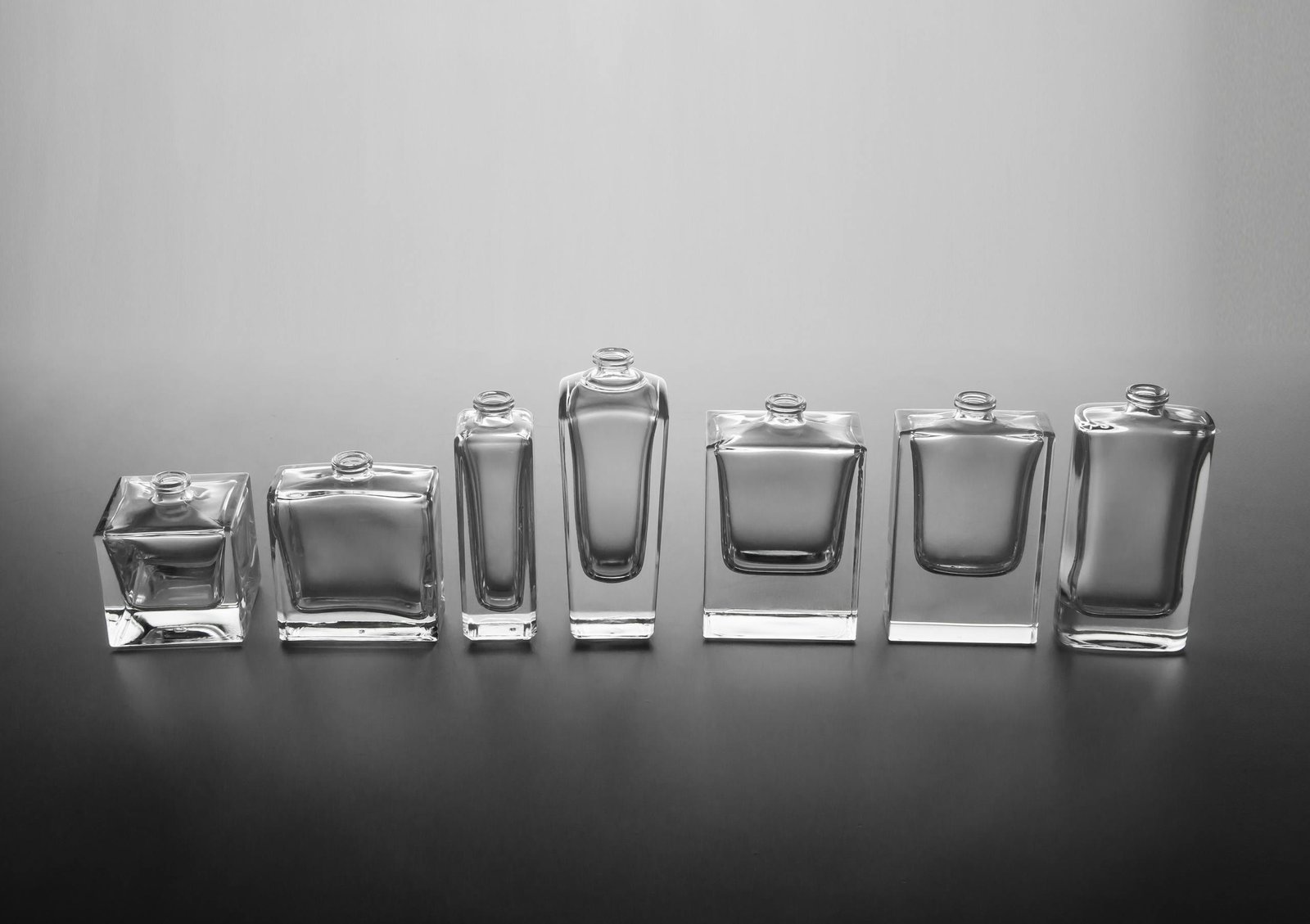 A sophisticated display of empty glass perfume bottles arranged against a neutral background, epitomizing minimalist elegance.