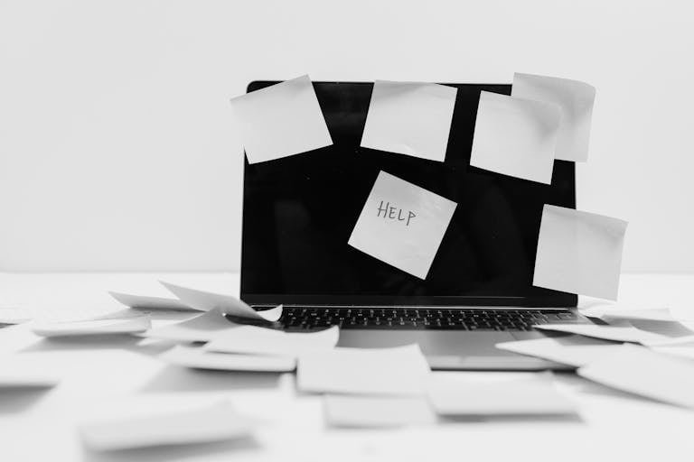 Monochrome image featuring sticky notes covering a laptop screen, symbolizing workplace chaos.