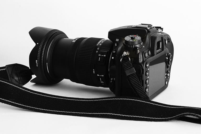 Close-up of a DSLR camera with lens and strap on a white background.
