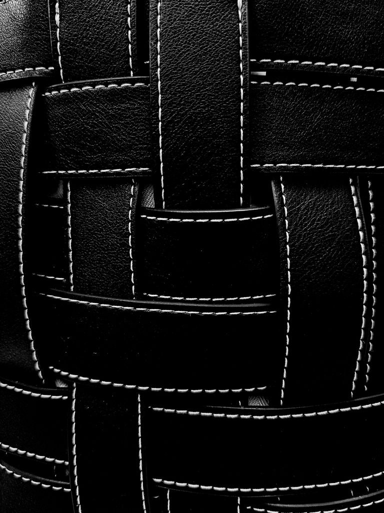 Detailed close-up of black leather weave texture with visible stitching.