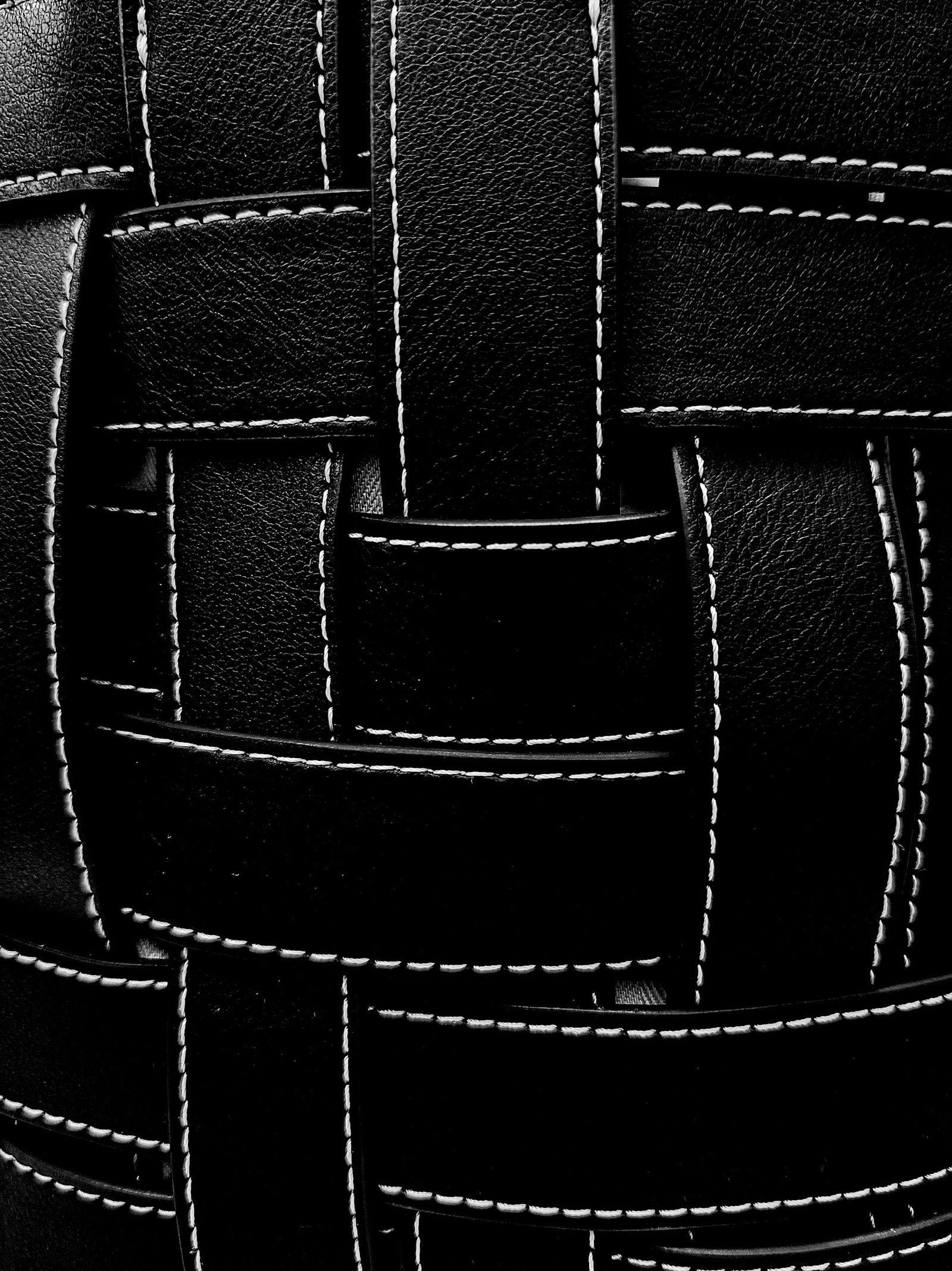 Detailed close-up of black leather weave texture with visible stitching.