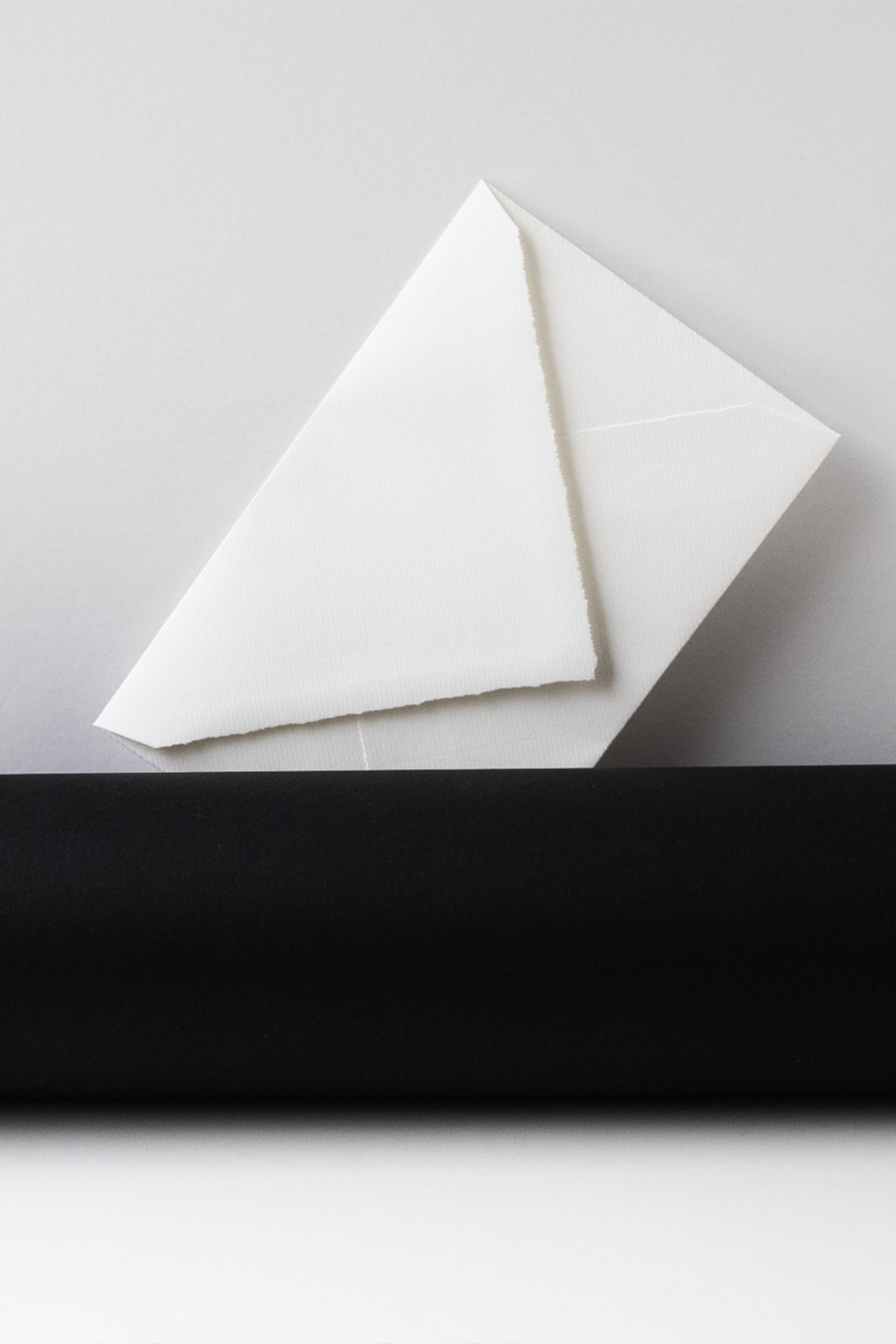 Elegant minimalist white envelope on a contrasting black surface, perfect for stationary themes.